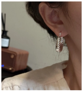 Détail macro de la boucle d'oreille créole croissant en argent S925 avec plis texturés
