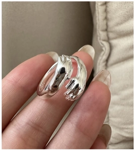Dettaglio macro dell'anello mani che si abbracciano in argento S925 con fascia aperta