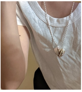 Gros plan du pendentif cœur bombé en argent S925 sur une chaîne à billes sur t-shirt blanc