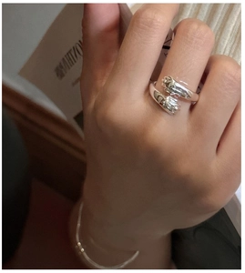 Dettaglio dell'anello mani che abbracciano in argento S925 e bracciale su mano con sfondo soft