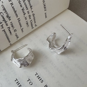Minimalist S925 sterling silver irregular C-shaped earrings with hammered texture on a book