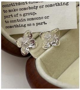 Macro shot of silver flower earrings with detailed textured petals on a jewelry box