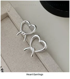 Macro shot of silver heart knot earrings with polished finish on a display tray