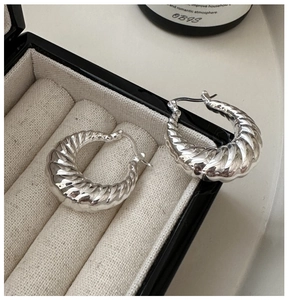 Vue macro des créoles croissant en argent avec texture spirale sur boîte en velours