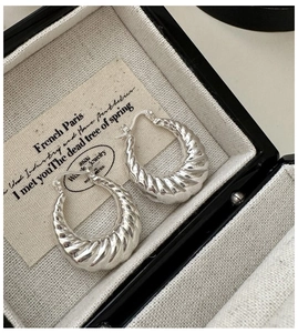 Détail de créoles croissant en argent sterling S925 dans une boîte à bijoux noire élégante