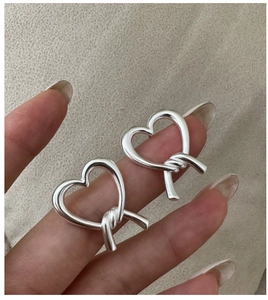 Detail of S925 sterling silver heart knot earrings with a matte brushed finish texture