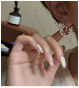 Detail of twisted silver hoop earrings and ring on a model in a cozy lifestyle setting