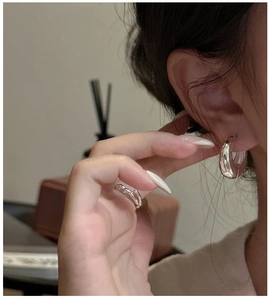 Primo piano di orecchini a cerchio spessi in argento S925 e anello testurizzato su modella