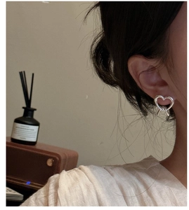 Detail showing an S925 sterling silver heart knot stud earring worn by a model