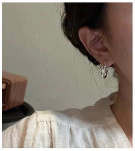 Detailed view of twisted knot silver earring on model for minimalist style