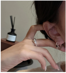 Detail of minimalist 925 silver croissant ring and thick hoop earrings on model