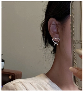 Detail of S925 sterling silver heart knot earring shown on an ear for a minimalist look