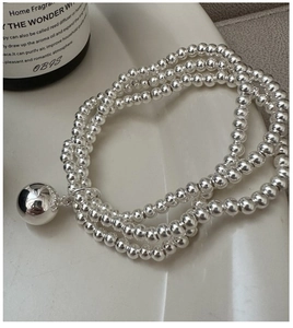 Detail of S925 sterling silver triple layer beaded bracelet with polished sphere pendant