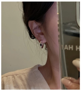 Close-up of a 925 sterling silver C-shaped heart earring with black onyx on model ear