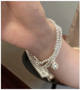Close-up of triple-layered S925 sterling silver beaded bracelet with ball pendant