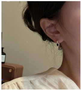 Close-up of 925 silver C-shape earrings with black onyx inlay on model's ear
