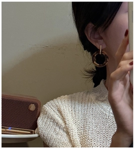 Detail shot of amber leopard-pattern hoop earrings with gold hooks on a model