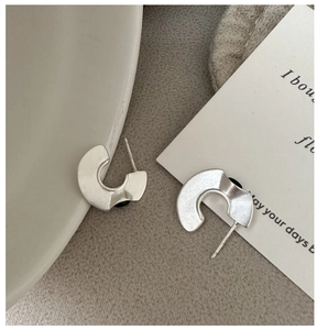 Macro shot of 925 silver irregular C-shape earrings with frosted finish and S925 stamp