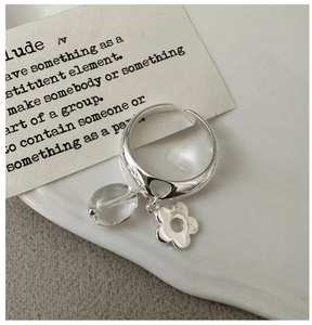 Macro detail of S925 silver ring featuring hollow flower and crystal pendant on tray