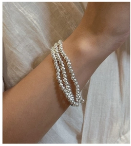 Detailed close-up of triple-layered S925 sterling silver beaded bracelet on wrist