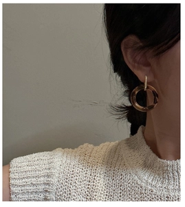 Detail view of model wearing minimalist resin leopard print hoop earrings with gold metal hook