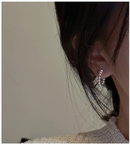 Detail view of a person wearing beaded sterling silver hoop earrings with minimalist texture