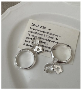 Detail of silver flower ring with white crystal charm on white vintage porcelain plate
