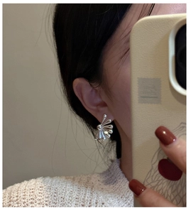 Close-up of S925 sterling silver fan-shaped earrings worn in a mirror selfie