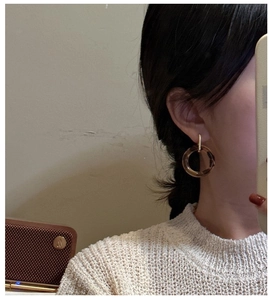 Close-up of amber resin hoop earrings with golden metal accents on a model