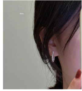 Detail of S925 sterling silver hoop earring with twisted rope texture on model's ear