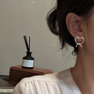 S925 sterling silver matte heart earrings with knot detail worn by a model