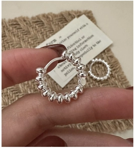 Macro view of S925 sterling silver beaded hoop earring held against a rustic background