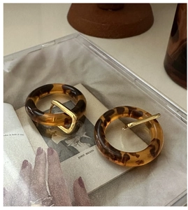 Macro shot of retro amber leopard print resin hoop earrings with golden metal accents