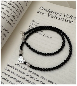 Détail du collier cœur en argent S925 avec perles d'onyx noires sur fond de livre français