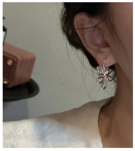 Détail de boucles d'oreilles fleur en argent portées par un mannequin sous lumière douce