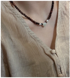 Vue détaillée du pendentif cœur en argent S925 sur un collier de perles rouge foncé