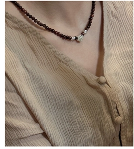 Détail du collier à pendentif cœur en argent sur perles foncées et lin