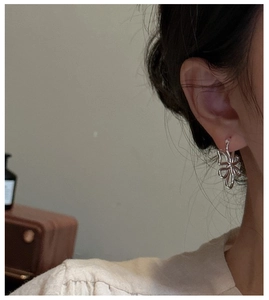 Détail de boucles d'oreilles papillon argentées portées par un mannequin au style élégant