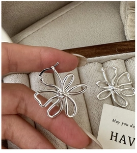 Vue macro des boucles d'oreilles fleur creuse en argent S925 avec finition métallique