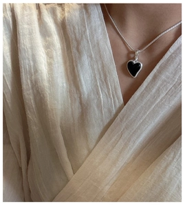 Gros plan d'un collier en argent S925 avec pendentif cœur en agate noire sur le cou