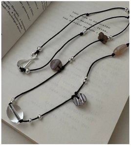 Detail of S925 silver beaded sweater necklace with butterfly charm on a book