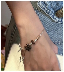 Detail of vintage handmade silver bead bracelet with natural brown stone and woven cord