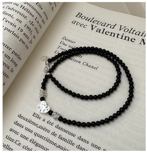 Gros plan d'un collier de perles noires avec pendentif coeur argenté sur un livre