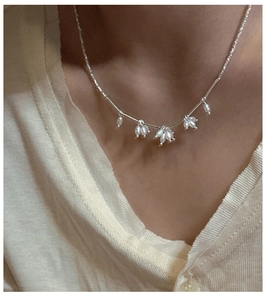 Close-up of S925 silver necklace with drop freshwater pearls on a white cardigan