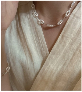 Close-up of floral pearl necklace and bracelet set worn on casual cotton fabric