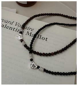 Détail de colliers de perles avec pendentifs coeur en argent texturé et accents vintage