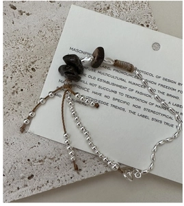 Detail of handcrafted S925 silver bracelet with natural stones and brown tassel cord