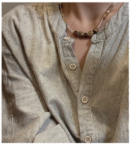 Detail view of S925 silver beaded necklace with tiger eye stones on linen shirt