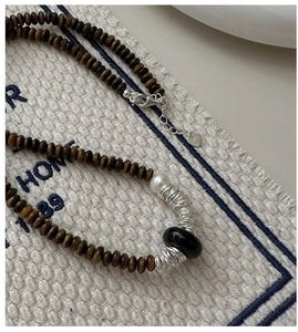 Détail du fermoir cœur en argent S925 et des perles de bois brun sur un collier rétro