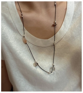 Detail of a long boho necklace with silver beads, agate stones and wooden discs on a cord
